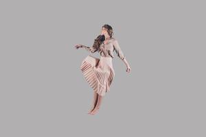 levitation. studio skott av attraktiv ung kvinna i skön klänning svävande i luft foto
