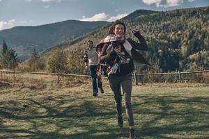 ung och sorglös. full längd av Lycklig ung par leende medan löpning på de dal i bergen utomhus foto