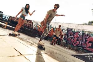 skridskoåkning är deras liv. full längd av ung människor skateboard medan hängande ut på de skridsko parkera utomhus foto