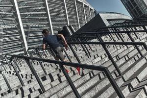 Träning till bli de bäst. full längd av ung man i sporter Kläder löpning upp de trappa medan utövar utanför foto