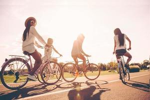 perfekt dag för cykling. låg vinkel se av ung människor ridning cyklar längs en väg och ser Lycklig foto