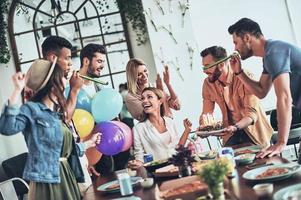 tid till göra en önskar. grupp av Lycklig människor fira födelsedag bland vänner och leende medan har en middag fest foto