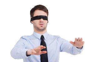 ser Nej möjlighet. ung affärsman i blind- stretching ut händer medan stående isolerat på vit foto