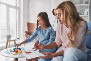 mor och dotter målning med fingrar och leende medan utgifterna tid på Hem foto