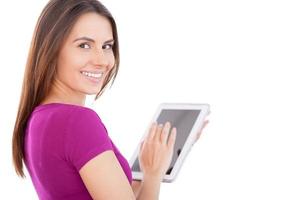 teknik bli lättare. glad ung kvinna använder sig av digital läsplatta och ser över axel medan stående isolerat på vit foto