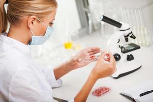 testning blod prover. topp se av ung kvinna forskare granskning blod medan arbetssätt i de laboratorium foto