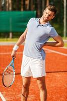 känsla smärta i hans tillbaka. närbild av tennis spelare rörande hans tillbaka och grimaserande medan stående på de tennis domstol foto