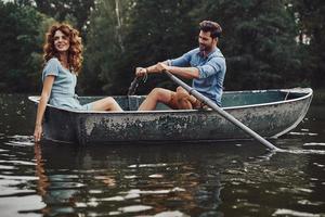 Bra gånger. skön ung par njuter romantisk datum medan rodd en båt foto