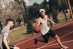 tryckande hård. två ung män i sporter Kläder spelar basketboll medan utgifterna tid utomhus foto