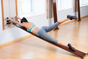kvinna stretching. sida se av skön ung kvinna i sporter Kläder håller på med stretching övningar foto