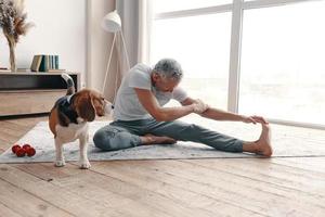 modern senior man i sport Kläder utövar på Hem nära hans hund foto