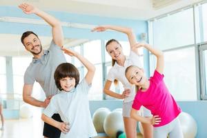 familj tränar. Lycklig sportig familj håller på med stretching övningar i sporter klubb foto