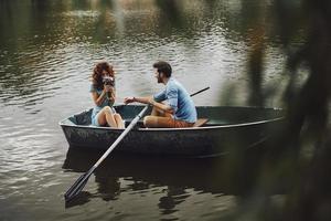 ren känslor. stilig ung man ger bukett till hans skön flickvän medan njuter romantisk datum på de sjö foto