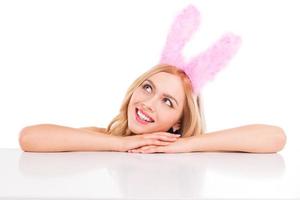 söt påsk kanin. skön ung blond hår kvinna med kanin öron lutande på de kopia Plats och leende foto