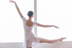 praktiserande i balett studio. bak- se av skön ung ballerina håller på med stretching övningar i balett studio foto