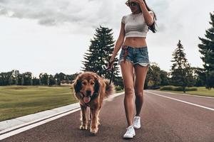 skön ung kvinna gående med henne hund medan utgifterna tid utomhus foto