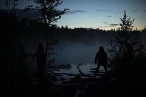 man i dimma på sjö. silhuett av man på Strand. utomhus- rekreation. foto