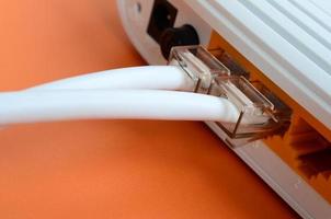 de internet kabel- pluggar är ansluten till de internet router, som lögner på en ljus orange bakgrund. objekt nödvändig för internet förbindelse foto