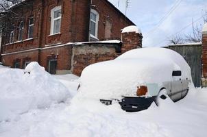 Kharkov, ukraina - december 4, 2016 en parkerad bil under en tjock lager av snö. konsekvenser av en stark och oväntat snöfall i ukraina foto