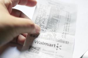 Washington USA - Mars 19 2022 mannens hand pekande till skatter på Walmart kvitton, skatter betalas, beskatta beräkningar. foto