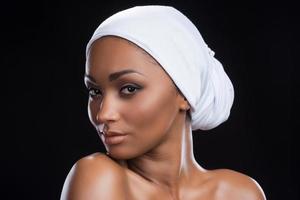 definierande skönhet. skön afrikansk kvinna bär en slöja och ser på kamera medan stående mot svart bakgrund foto