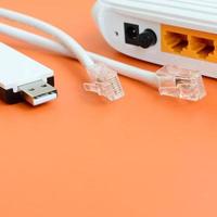 internet router, bärbar uSB Wi-Fi adapter och internet kabel- pluggar lögn på en ljus orange bakgrund. objekt nödvändig för internet förbindelse foto