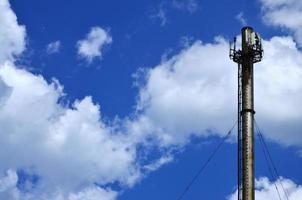 hög metall skorsten av industriell växt med stege i de form av metall tandställning mot de bakgrund av en molnig blå himmel foto