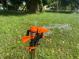 automatisk grön gräs sprinkler, vatten spruta för vattning gräsmatta växter foto