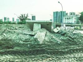 konstruktion landskap. byggnad material, bitar av betong, metall ramar lögn på de sand. stor och tung sopor, kastas på de jord. ekologisk stänga av, landa förorening foto