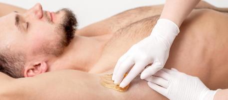 kosmetolog applicering vax klistra på manlig armhåla foto
