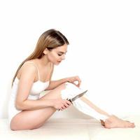 kvinna rakar henne ben med en kniv foto
