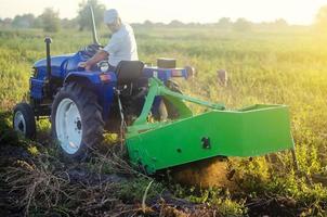 jordbrukare på en traktor gräver ut potatisar från jord. extrahera rot grönsaker till yta. jordbruk och jordbruksmark. skörd potatisar i höst. förenkla hastighet upp arbete med teknologi och maskiner. foto