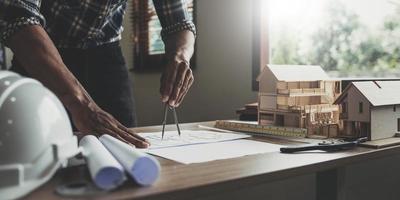 begrepp arkitekter, ingenjör innehav penna pekande Utrustning arkitekter på de skrivbord med en plan i de kontor, årgång, solnedgång ljus.selektiv fokus foto