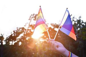 regnbåge flagga och armband innehav i händer, mjuk och selektiv fokus, begrepp för lgbtq kön fester och kallelse Allt människor till respekt mänsklig rättigheter i stolthet månad runt om de värld. foto