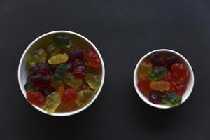 gelé marmelad björnar i en keramisk kopp på en svart bakgrund. marmelad färgrik godis närbild. foto