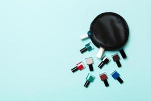 topp se av kosmetika väska med fallen ut färgrik nagel polermedel på blå bakgrund. skön naglar begrepp med tömma Plats för text foto