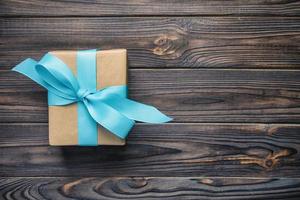 papper gåva låda med blå band på mörk trä- bakgrund jul närvarande begrepp, årgång, tonad topp se med kopia Plats foto