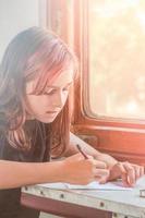 de flicka sitter i de tåg förbi de fönster och skrivningar på papper. Tonårs flicka resa. foto