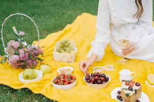 sommar picknick i natur med kaka, juice och frukt på en gul filt bland de grön gräs. utomhus- aktiviteter foto