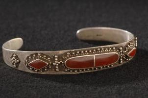 ett antik, elegant armband med gravyr och dyrbar röd stenar isolerat på en svart bakgrund foto