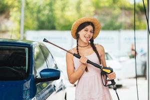 kvinna med hög tryck slang på bil tvätta foto