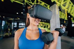 kvinna bär glasögon av de virtuell verklighet utövar med hantlar foto