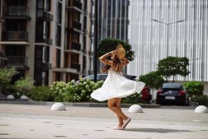 skön Söt kvinna i vit klänning gående på stad gata foto