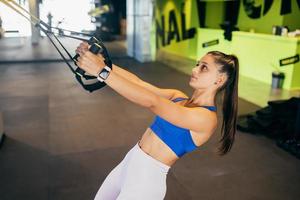 kvinna håller på med övningar med trx kondition remmar i de Gym foto