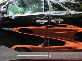 reflexion av ett orange bil på en svart skåpbil foto