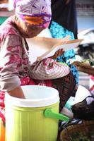 magelang, Indonesien, 2022-an gammal indonesiska kvinna är framställning pecel maträtter för kunder. pecel foto