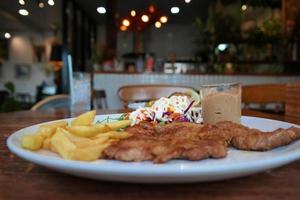 saftig svart peppar fläsk biff med frites och sallad foto