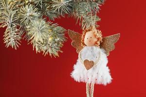 vit ängel leksak på en jul träd på en röd bakgrund. fri Plats. foto