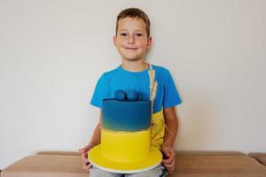 ukrainska pojke unge fira födelsedag innehav stor kaka med flagga av ukraina. foto