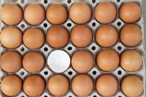 stänga upp av rå brun ägg i ett ägg kartong, ett ägg är bruten foto